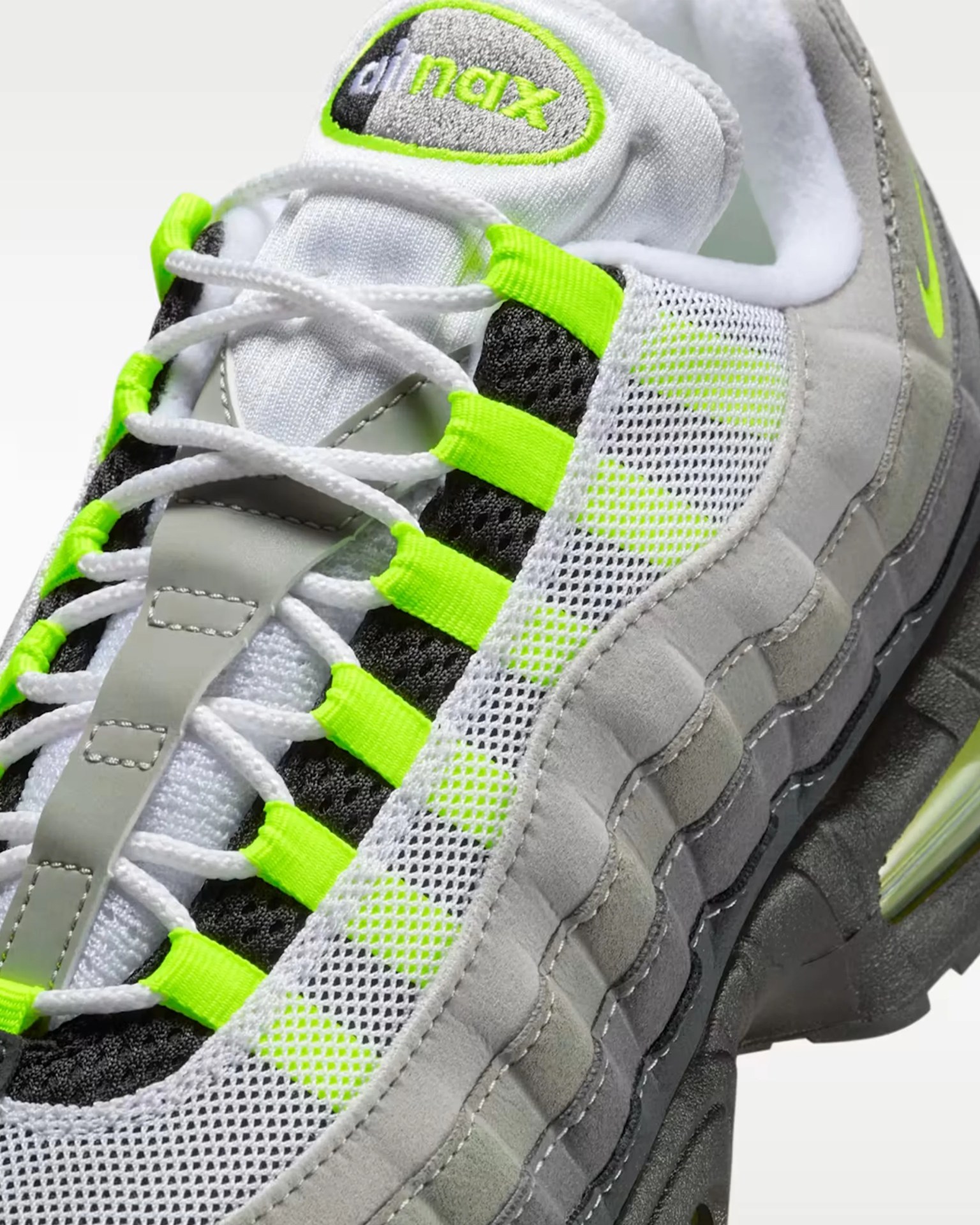 Close-up of a white and gray Nike Air Max sneaker with neon green accents and white laces.