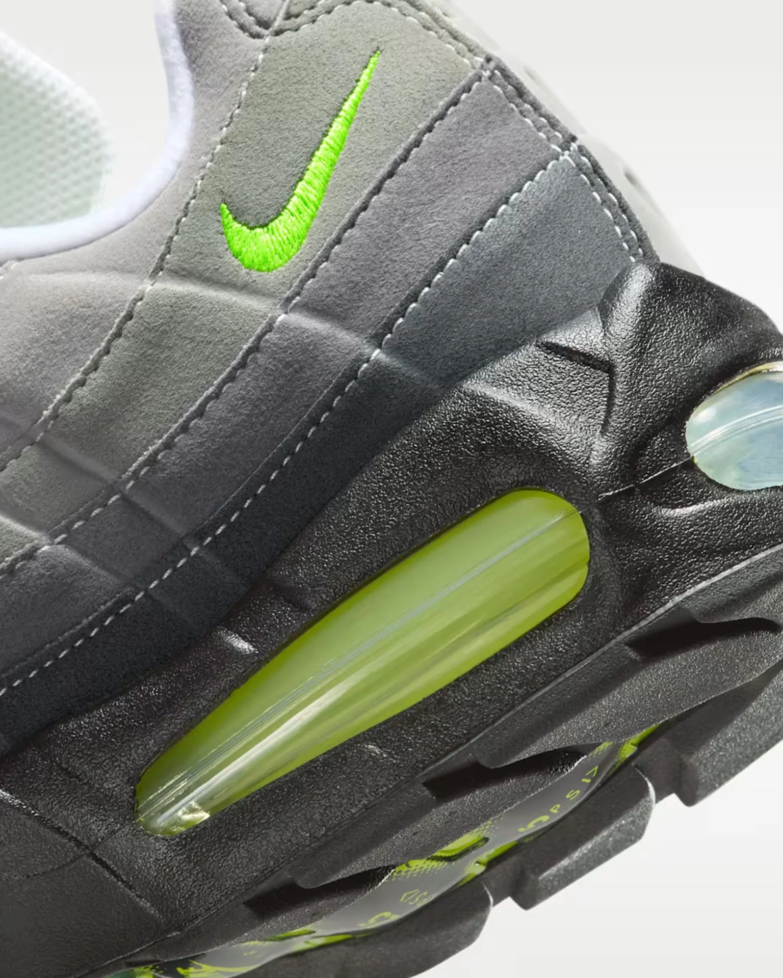 Close-up of a gray and black Nike sneaker heel with neon green air cushion and embroidered green Nike swoosh.
