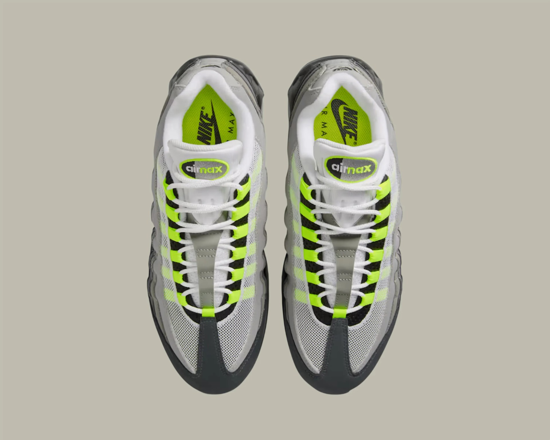 Pair of white and gray Nike Air Max sneakers with neon yellow accents viewed from above.