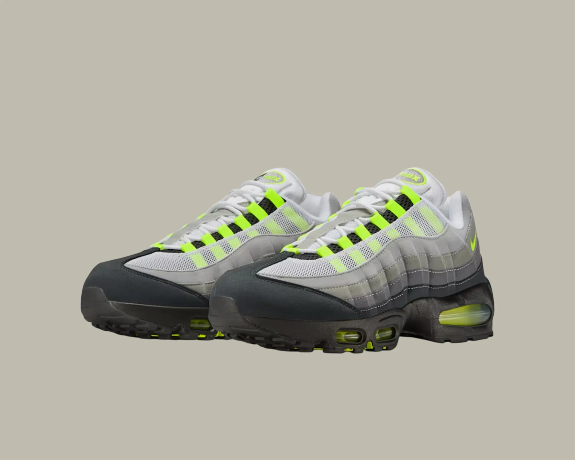 Pair of Nike Air Max 95 sneakers in white, grey, black, and neon yellow accents on a neutral background.