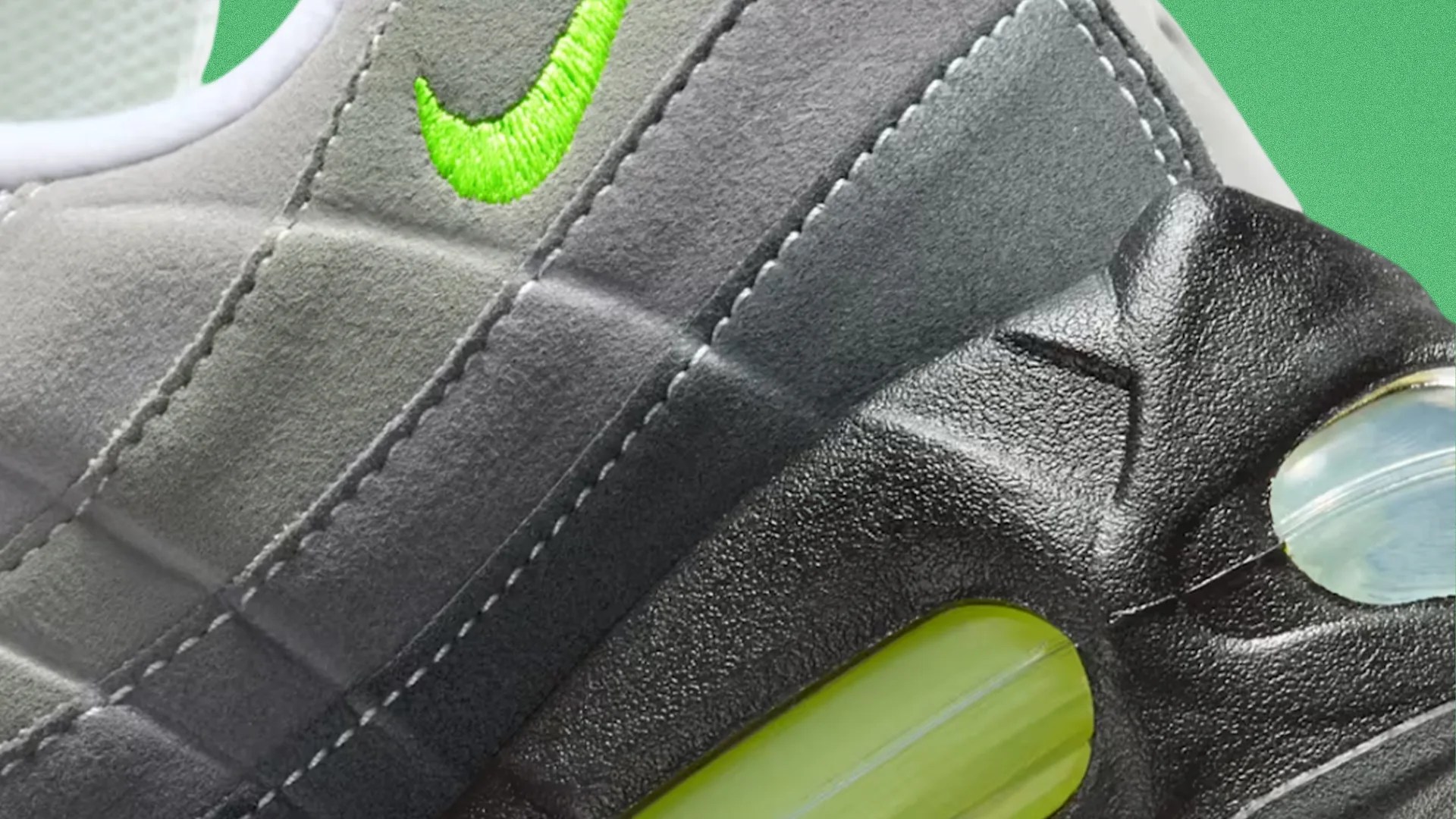 Close-up of gray suede sneaker with neon green embroidered Nike swoosh and visible air cushion in black sole.