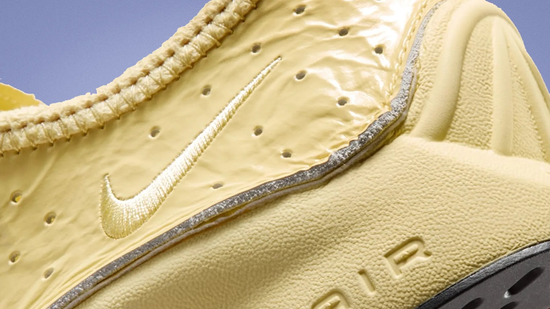 Close-up of a yellow Nike Air sneaker showing the embroidered swoosh and textured sole.
