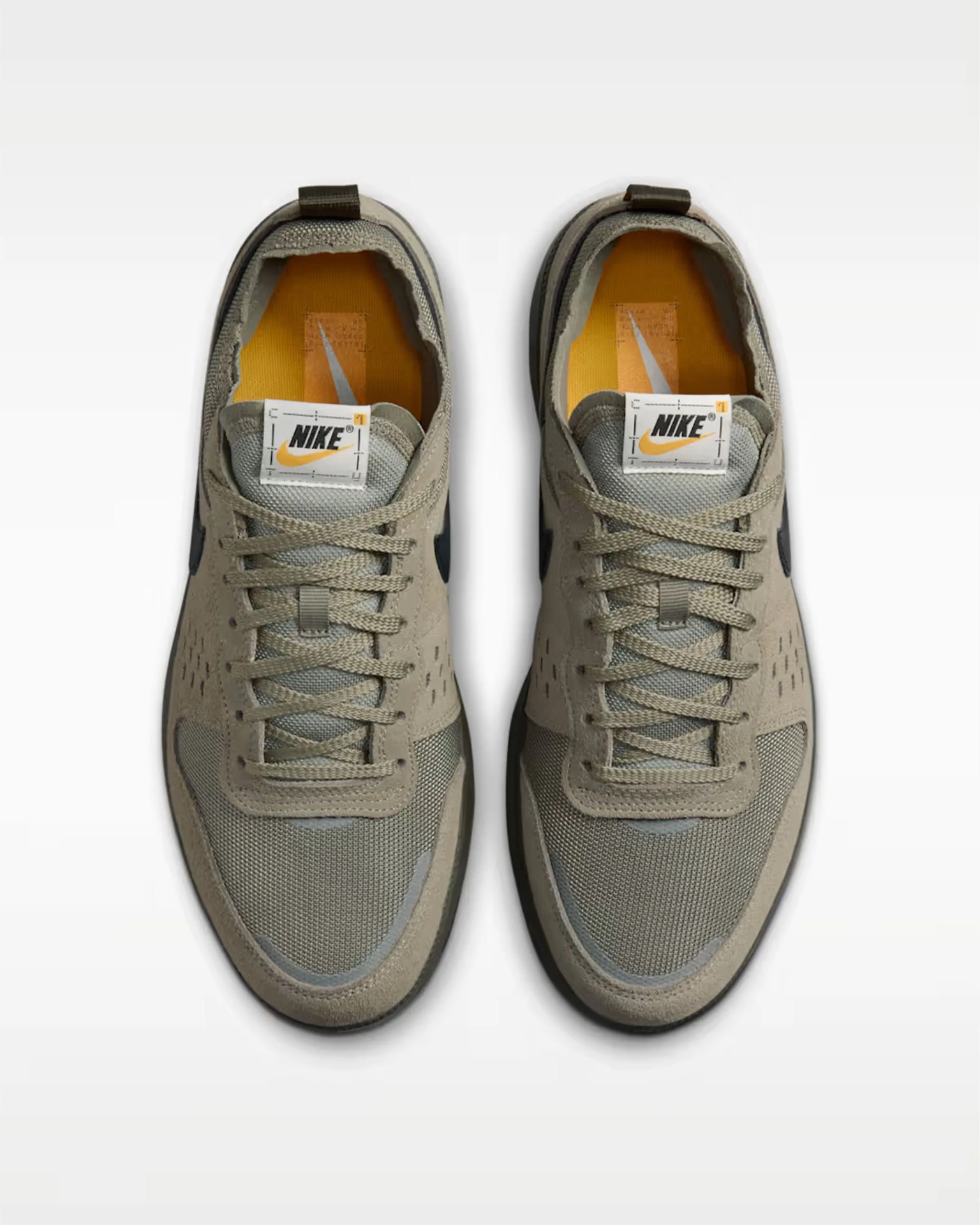 Pair of beige and gray Nike sneakers with black swoosh logos and orange insoles, viewed from above.