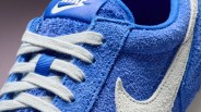 Close-up of a blue Nike sneaker with white laces and a white textured Nike swoosh.