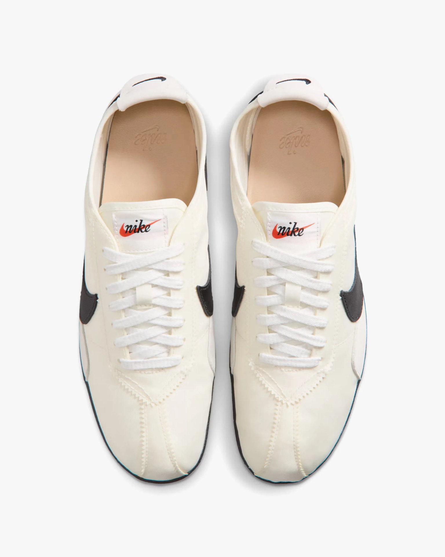 Pair of white Nike sneakers with black swoosh logos and white laces, viewed from above.