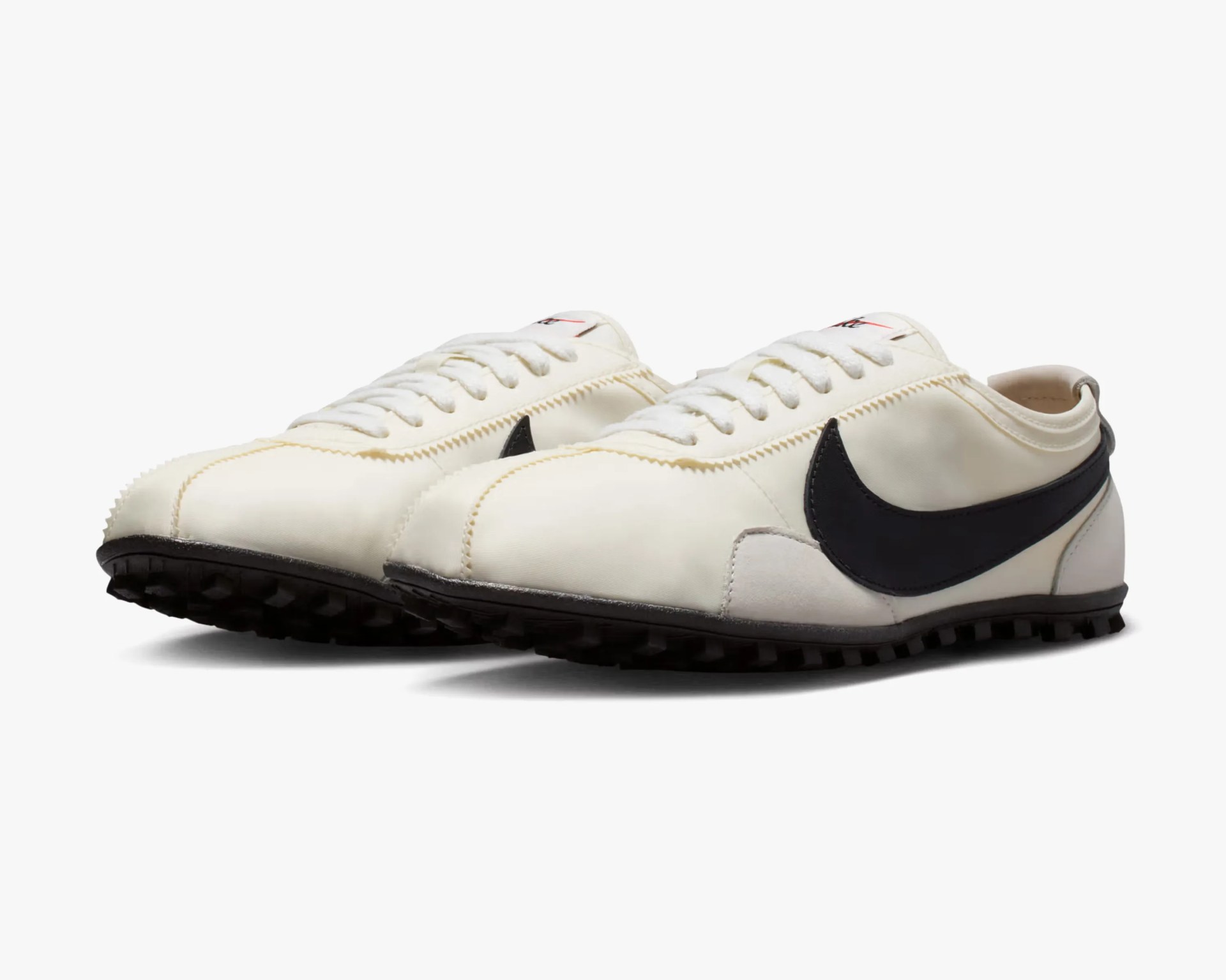Pair of off-white Nike sneakers with black swoosh logos and black textured soles on a white background.