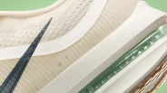 Close-up of a beige Nike sneaker with a black swoosh and visible green Zoom Air cushioning in the sole.