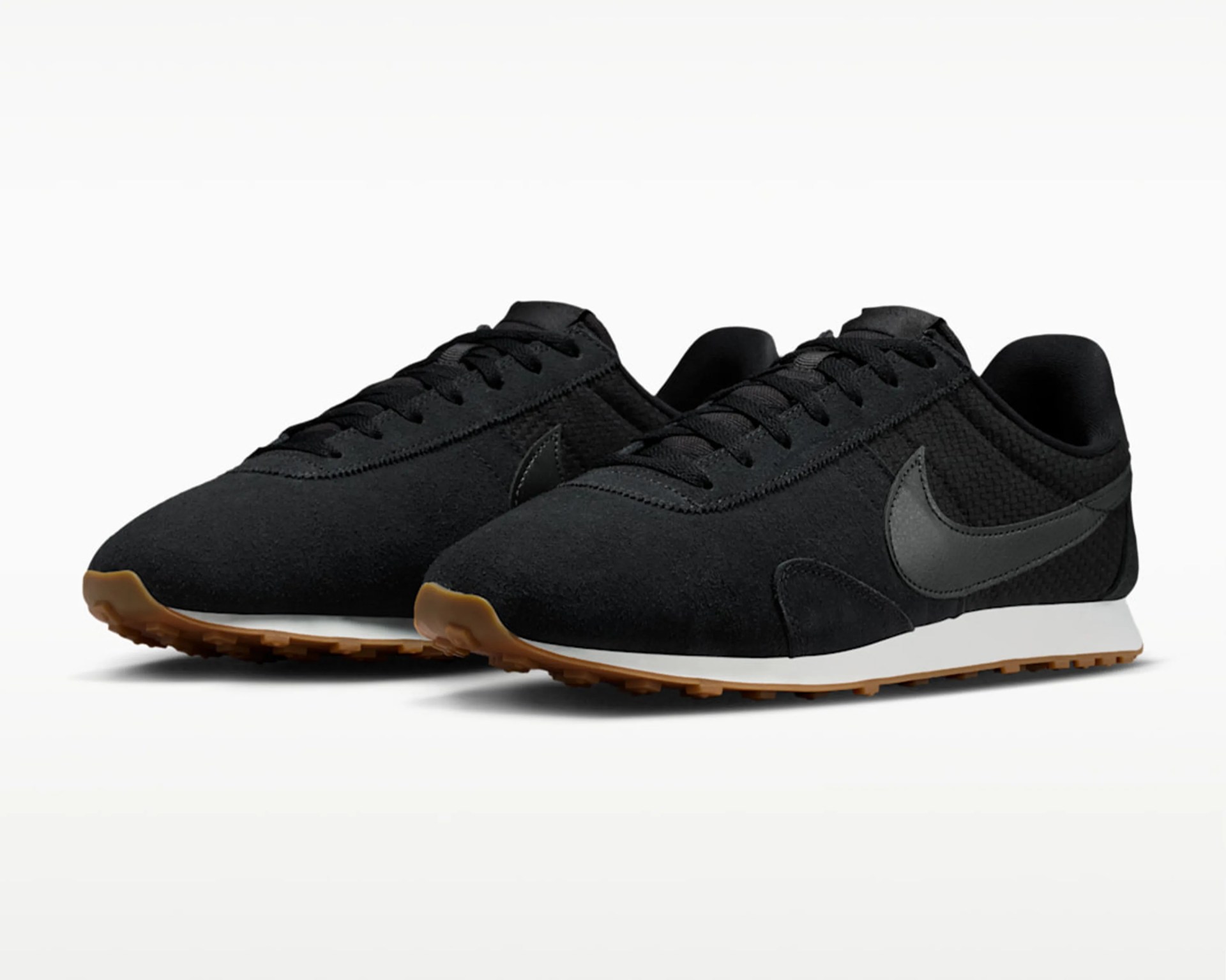 Pair of black Nike sneakers with textured fabric, leather swoosh, white midsoles, and gum rubber outsoles.