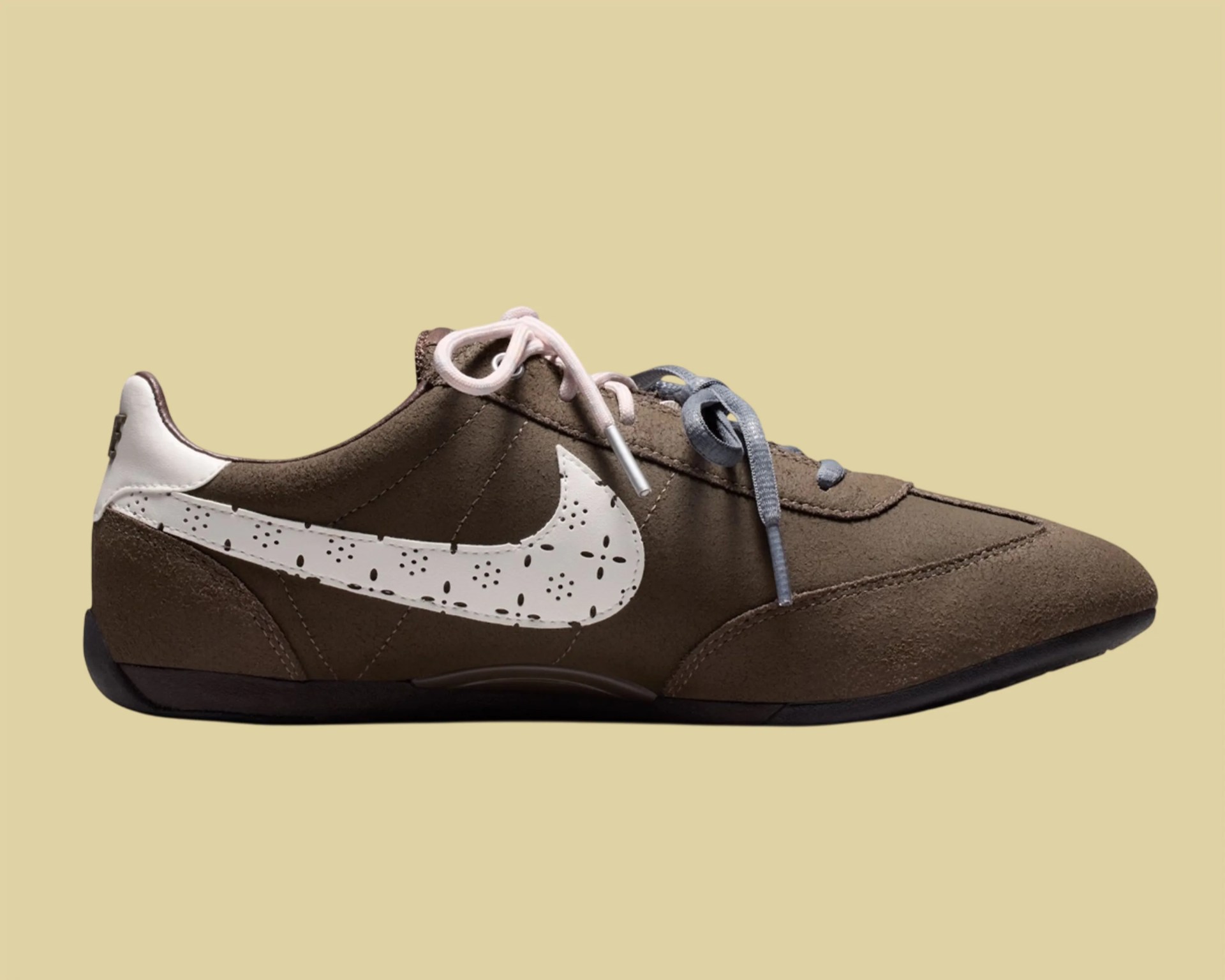 Brown suede Nike sneaker with white perforated swoosh and mismatched pink and gray laces.