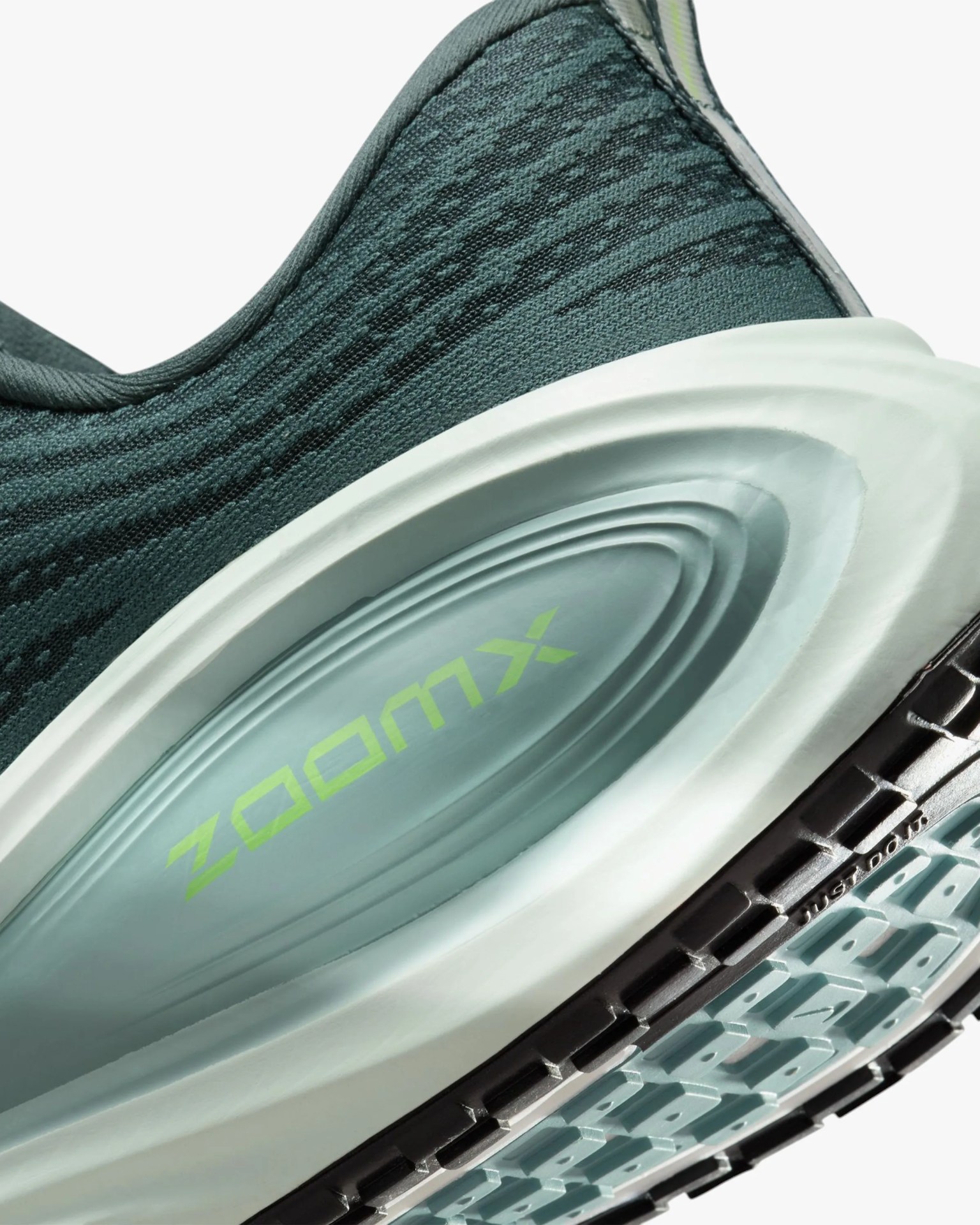 Close-up of a teal and black Nike ZoomX running shoe midsole with visible ZoomX cushioning and textured outsole.