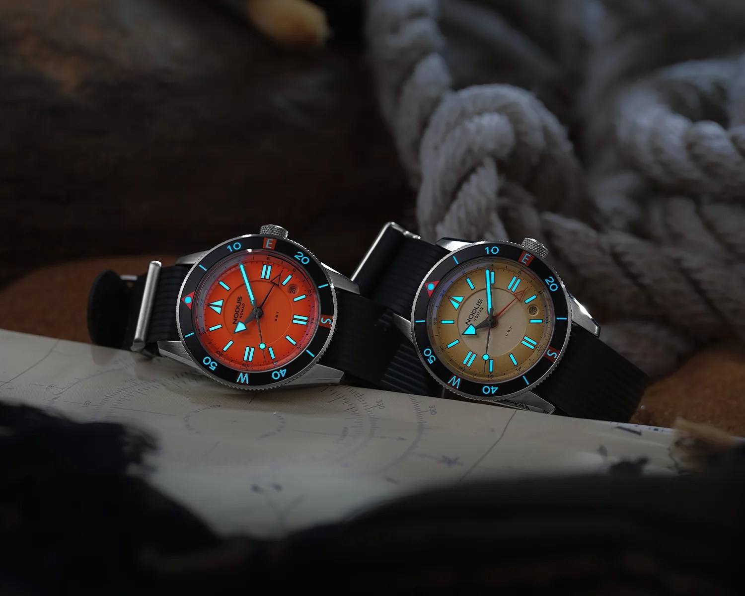 Two wristwatches with black straps, one with an orange dial and the other with a beige dial, both featuring glowing blue hour markers.