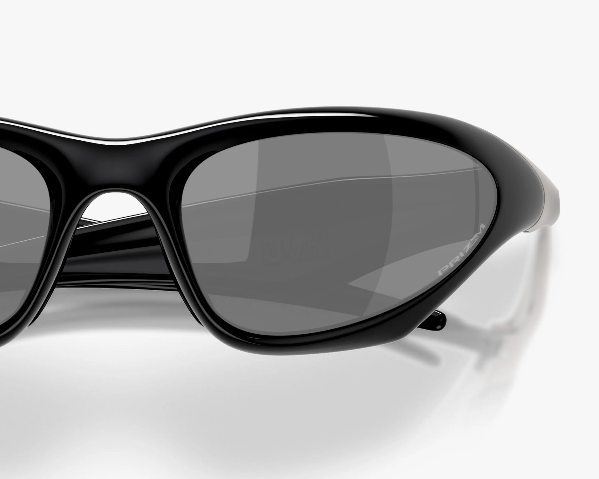 Close-up of black oval sunglasses with dark gray lenses and "PRIZM" text on the right lens.