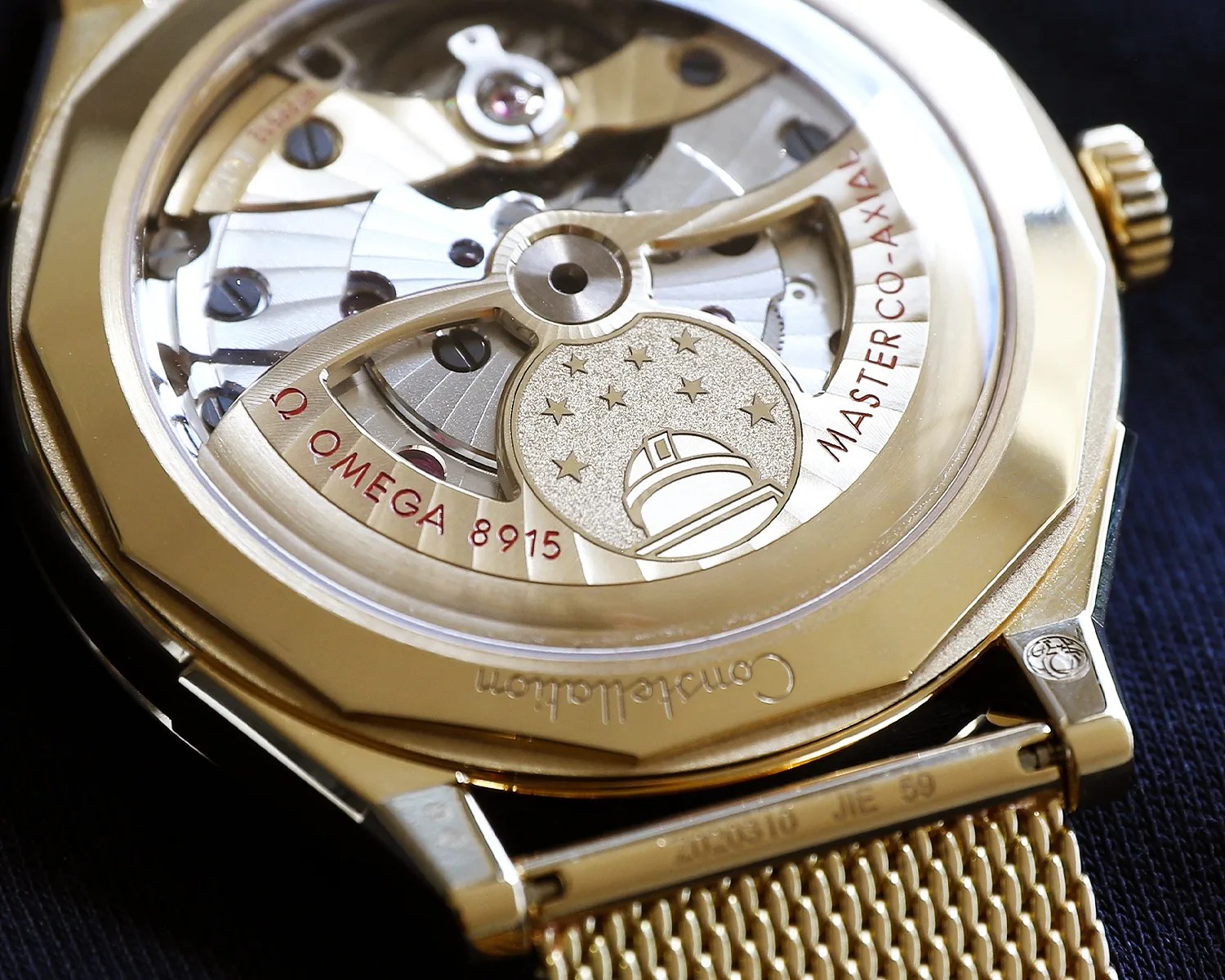 Close-up of the gold Omega watch back showing the intricate Master Co-Axial 8915 movement with a star and observatory emblem.