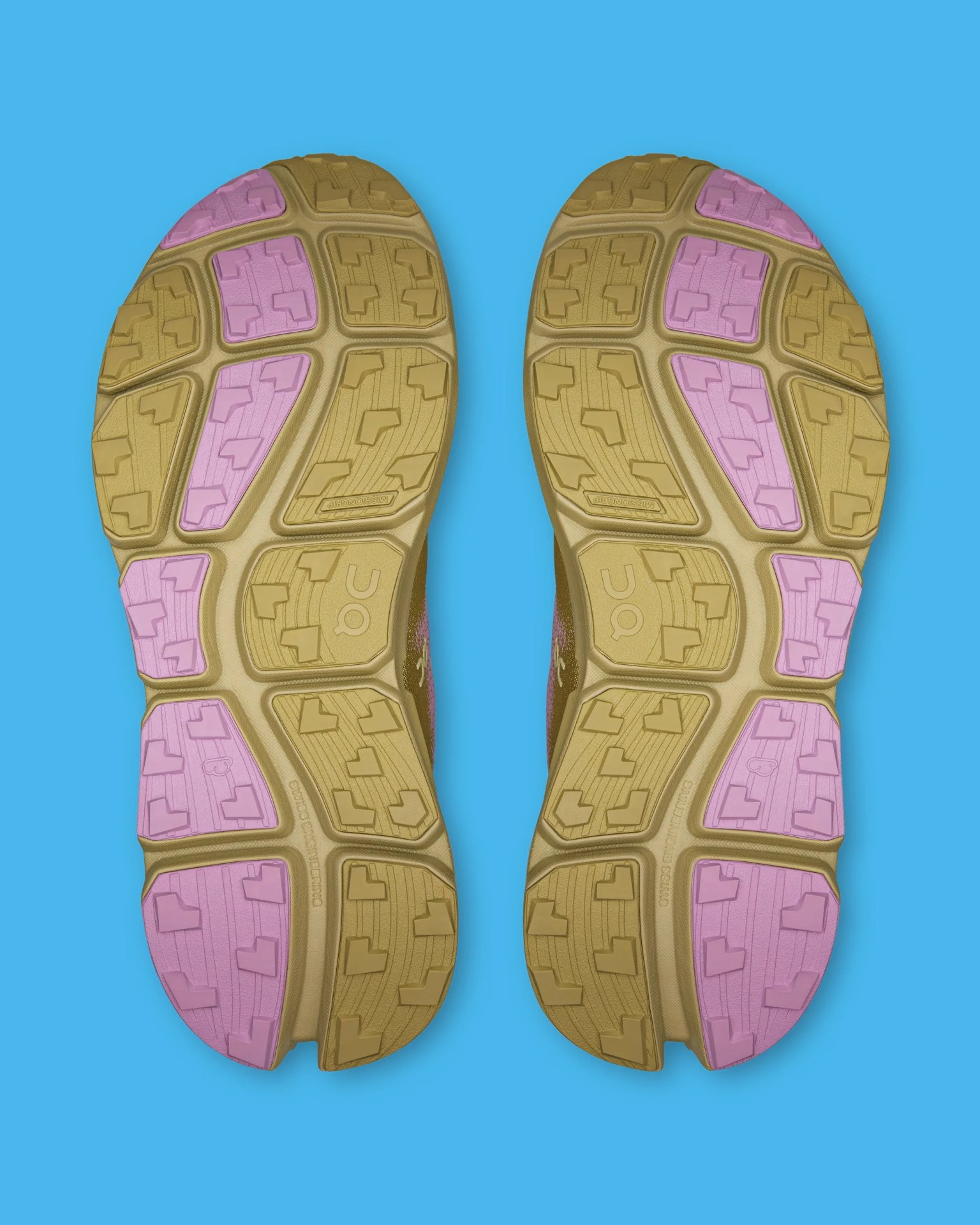 Outsole of a pair of running shoes with tan and pink rubber tread on a blue background.