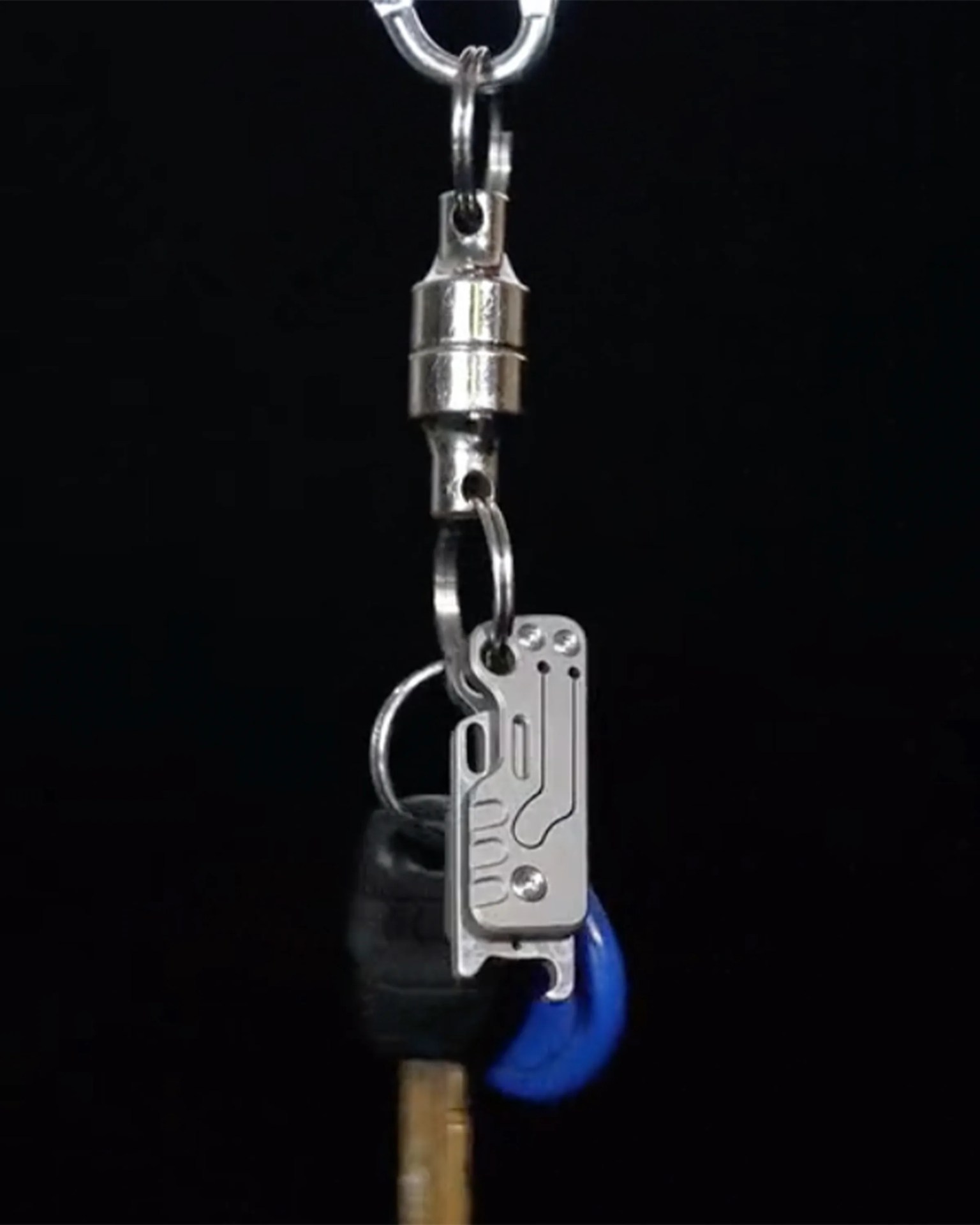 Silver metal keychain with a circuit board design attached to a keyring and a key against a black background.