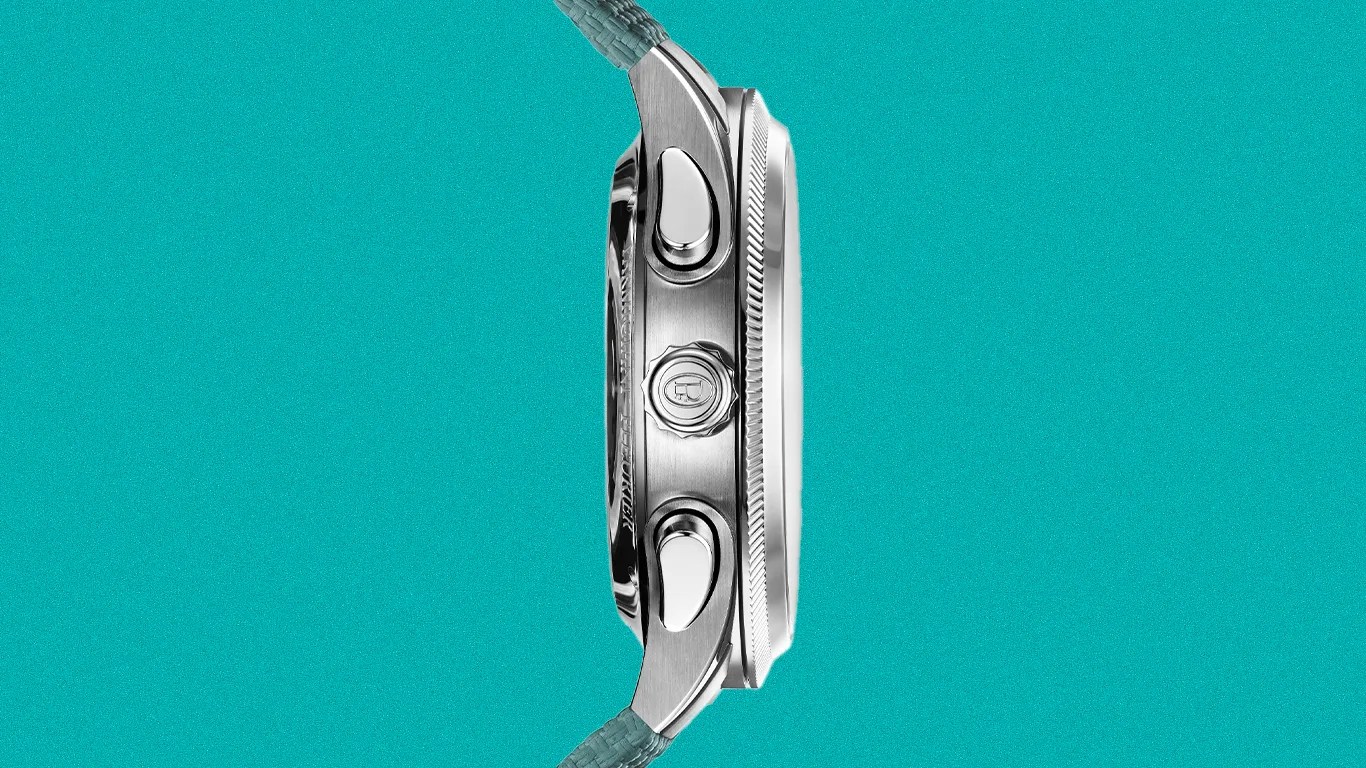 Side view of a silver stainless steel watch case with two push buttons and a crown on a teal woven strap.