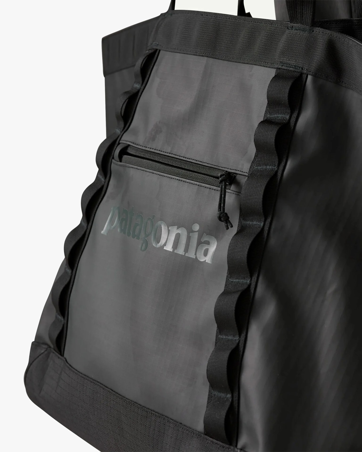 Black Patagonia tote bag with front zip pocket and wavy black webbing straps.