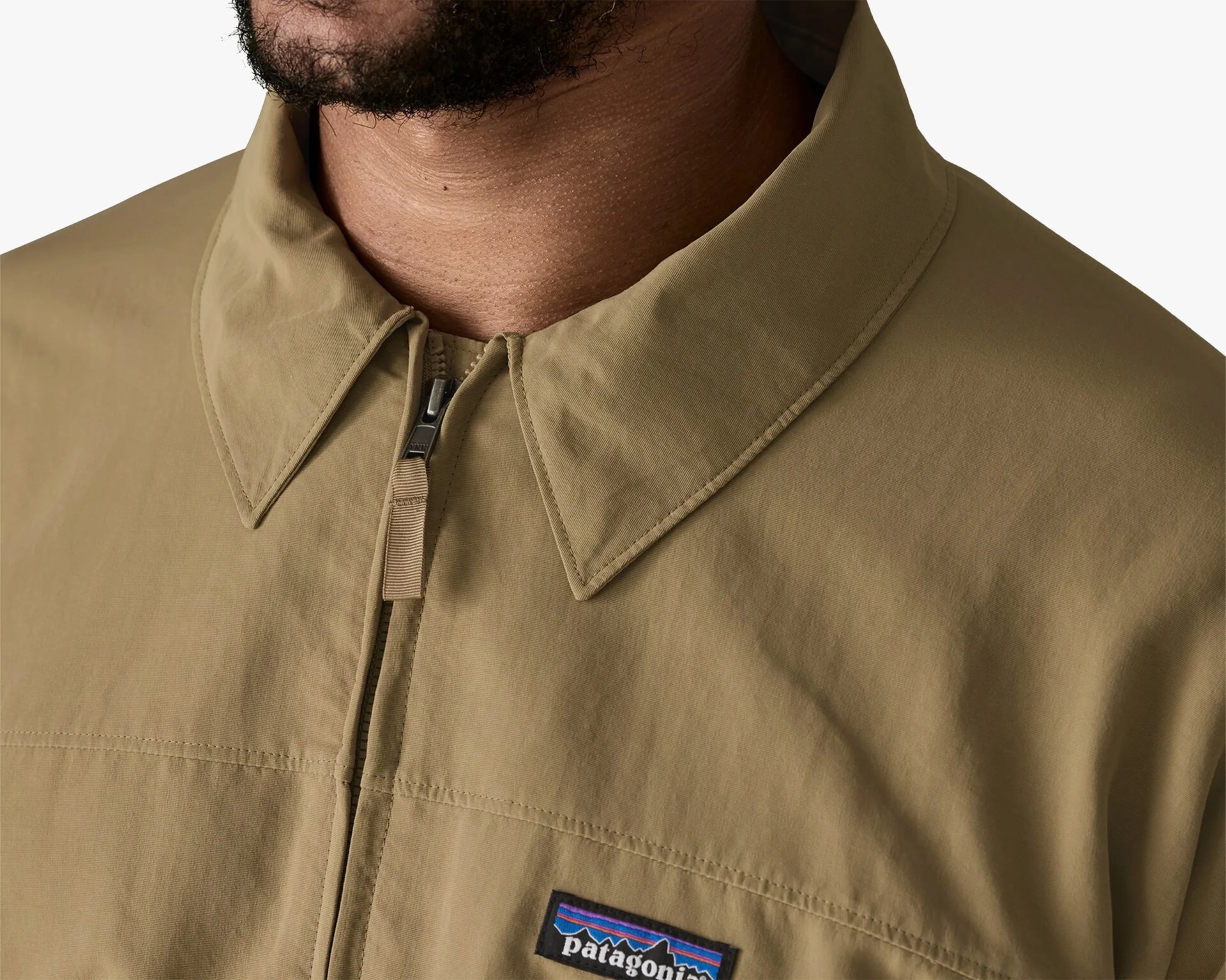 Close-up of a tan Patagonia jacket with a pointed collar and front zipper.