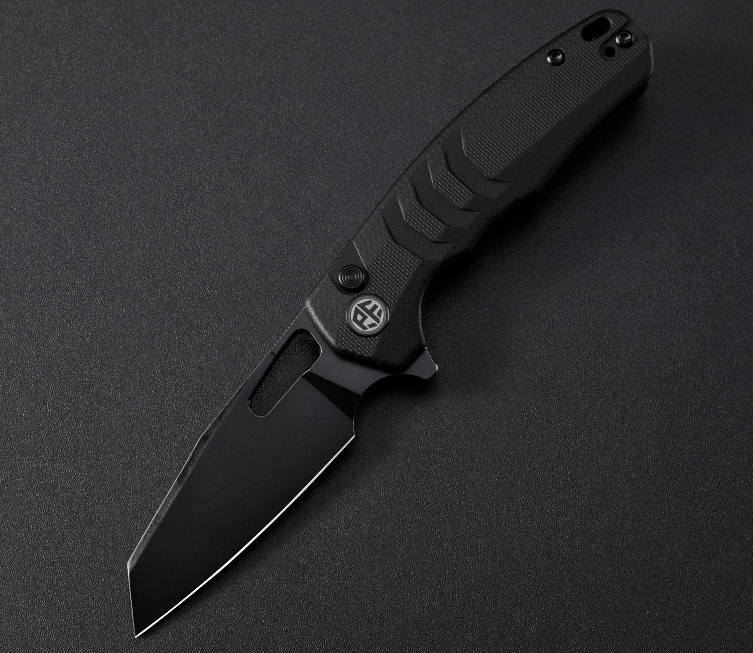 Black folding knife with textured handle and tanto-style blade on a dark surface.