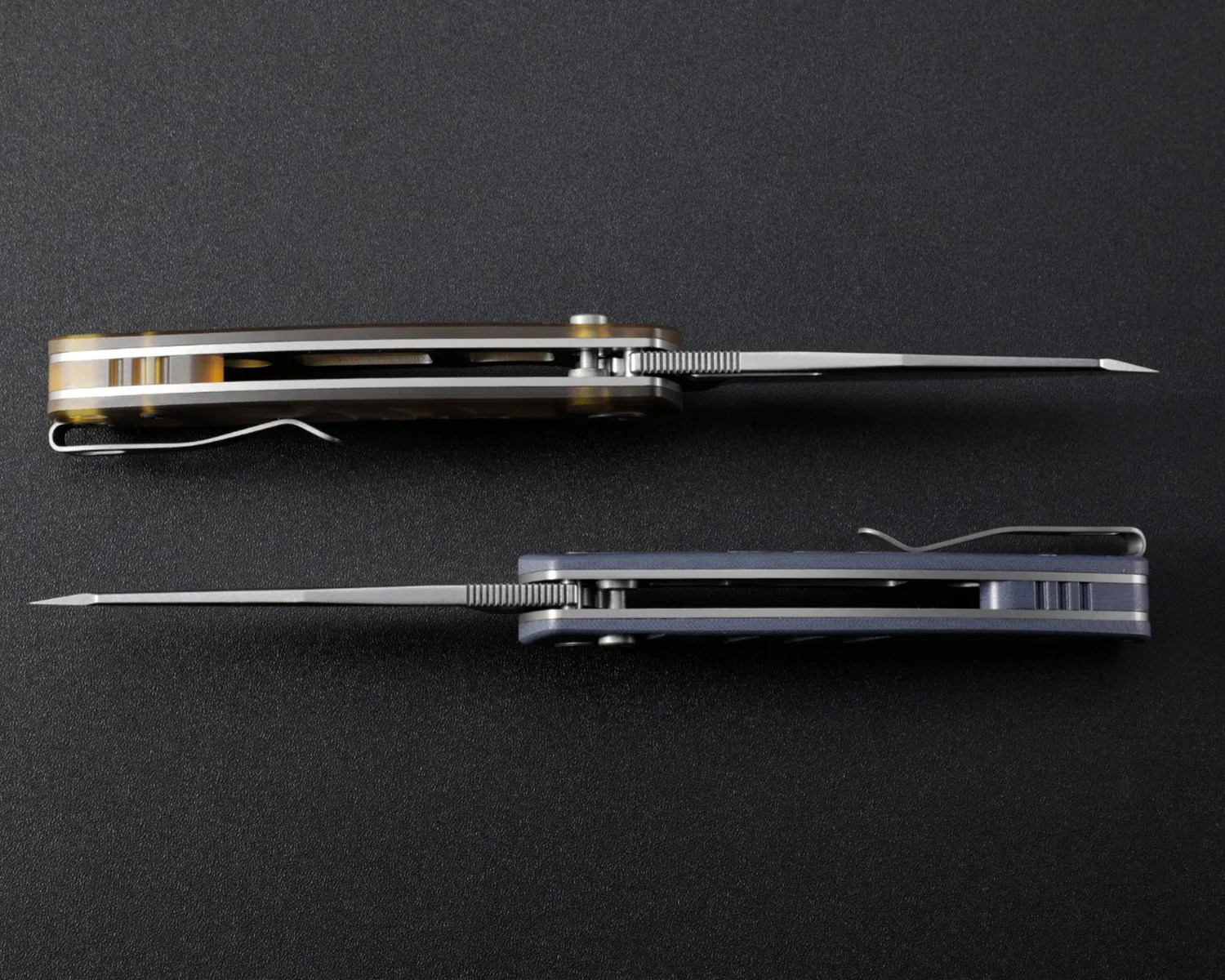 Two folding knives with partially open blades, one with a brown handle and the other with a blue handle, shown from the side on a black surface.