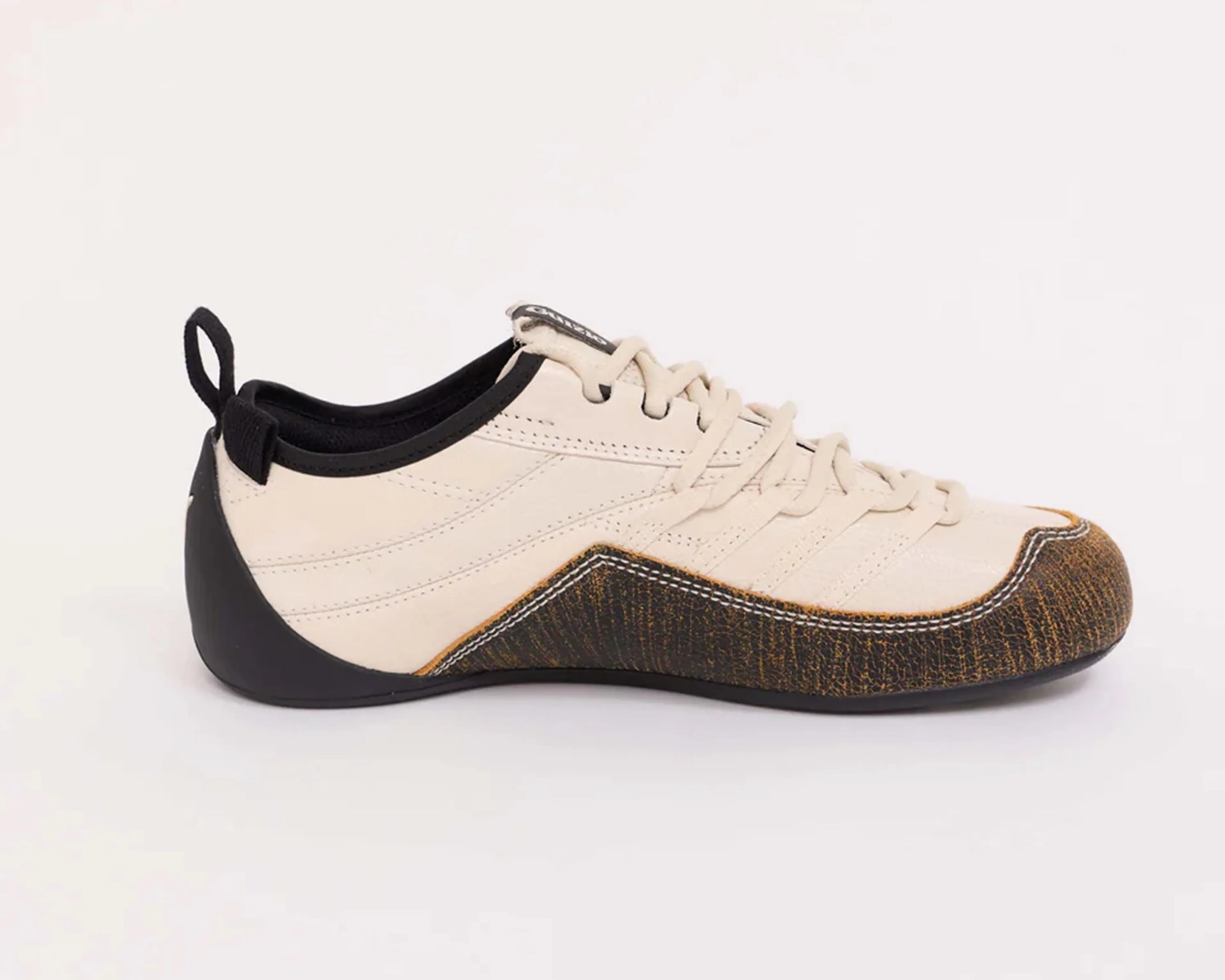 Beige and black low-profile sneaker with textured brown toe cap and black heel counter.