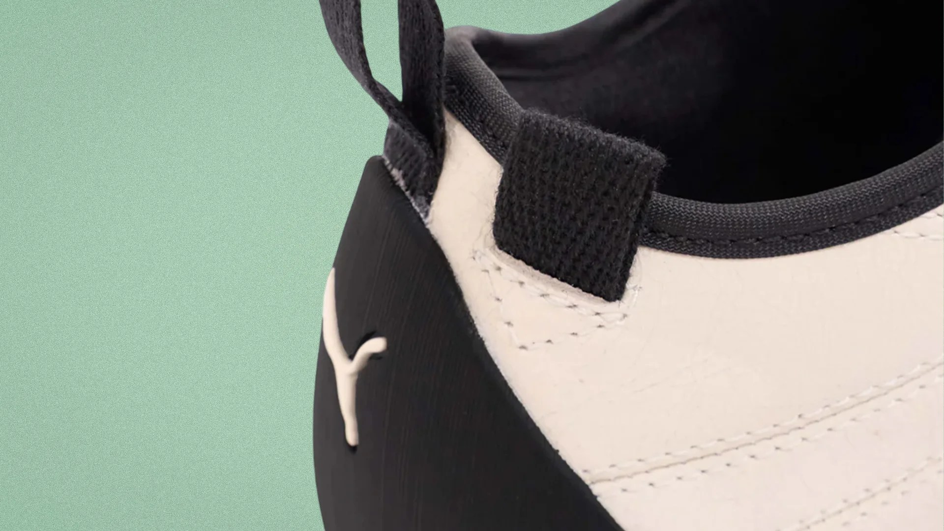 Close-up of the heel area of a white and black Puma sneaker with a black pull tab and Puma logo on the black heel counter.