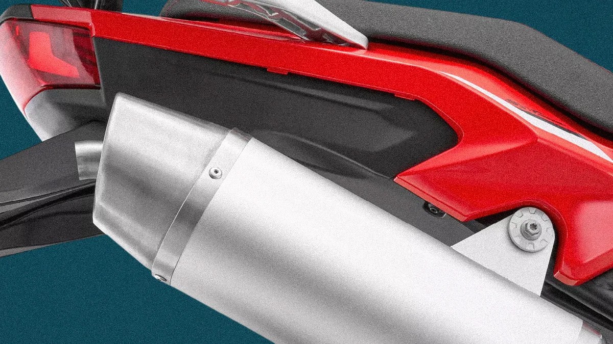 Close-up of a silver motorcycle exhaust pipe attached to a red and black bike body.