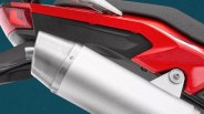 Close-up of a silver motorcycle exhaust pipe attached to a red and black bike body.