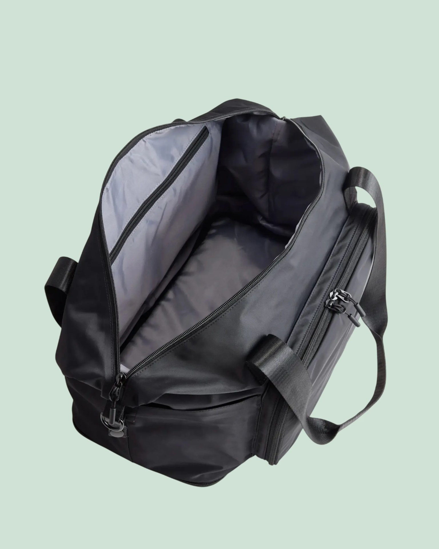 Black duffel bag with dual handles and a zippered main compartment open to show a gray interior pocket.