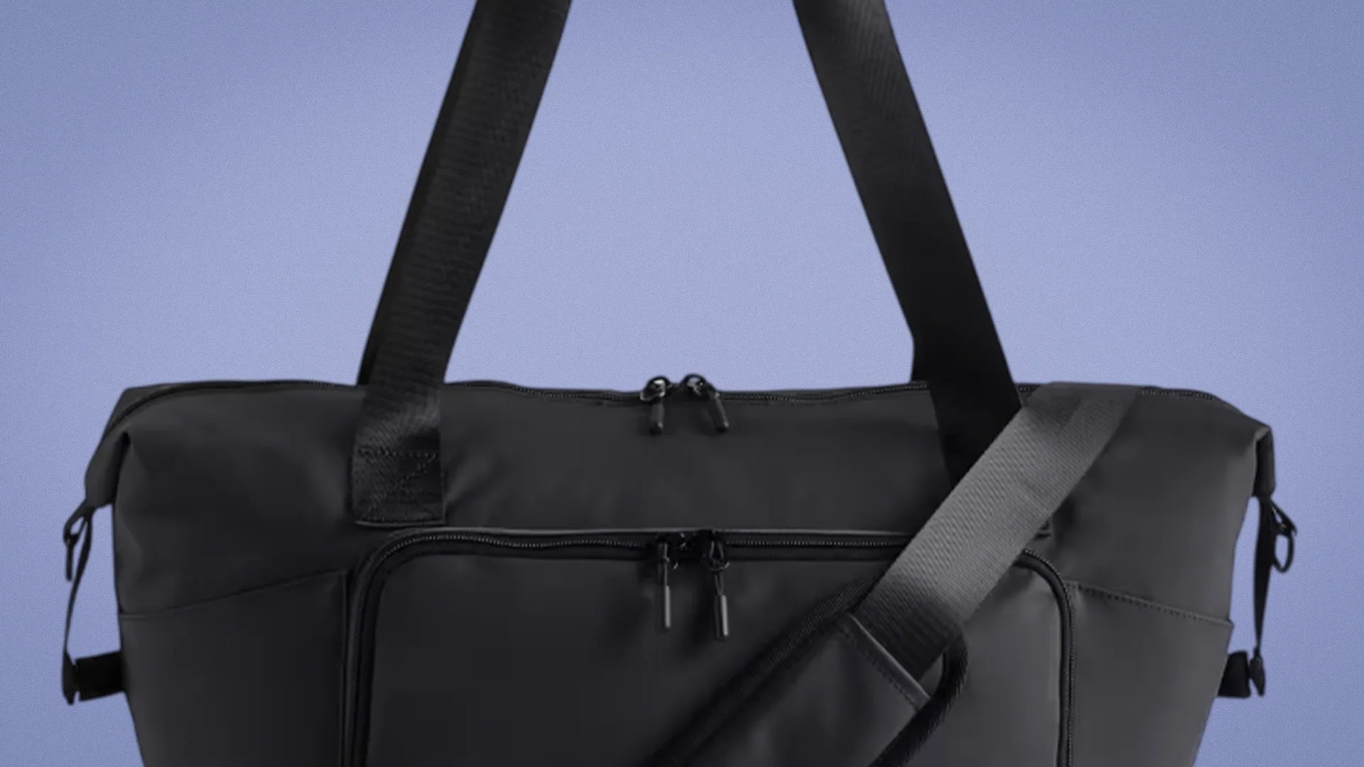 Black duffel bag with dual zipper closures and adjustable shoulder strap against a blue background.