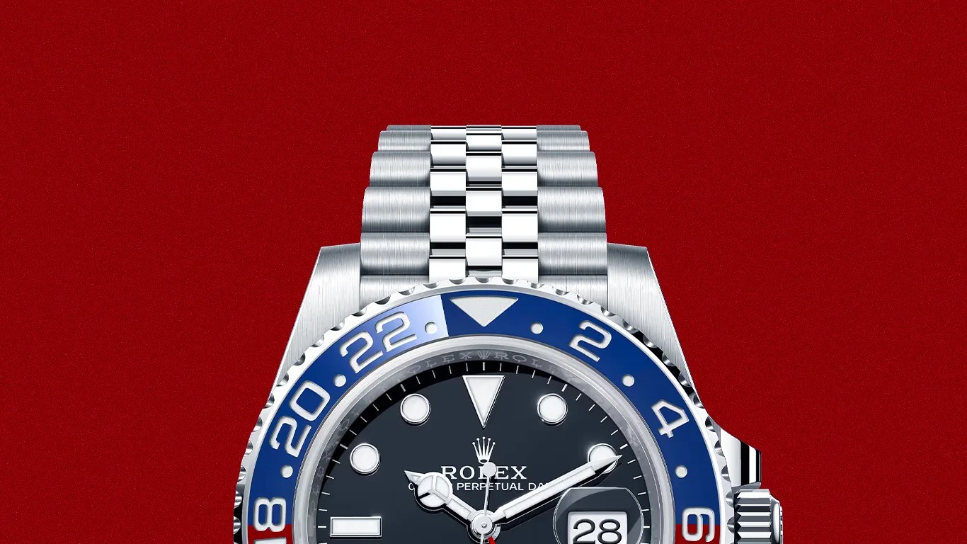 Stainless steel Rolex watch with blue and red bezel and black dial showing date 28 on red background.