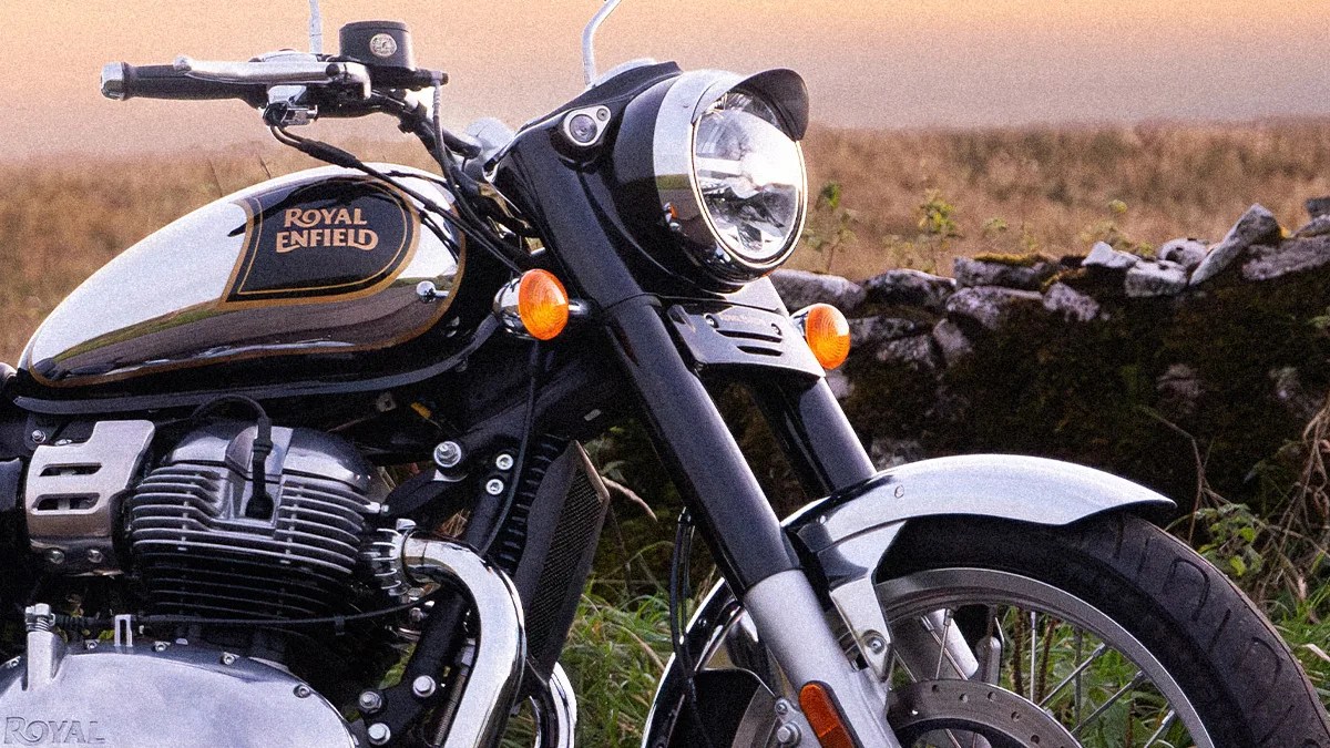 Close-up of a black and chrome Royal Enfield motorcycle front with headlight, orange indicators, and part of the fuel tank.