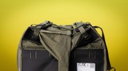 Olive green and black checkered fabric backpack with adjustable straps against a yellow background.