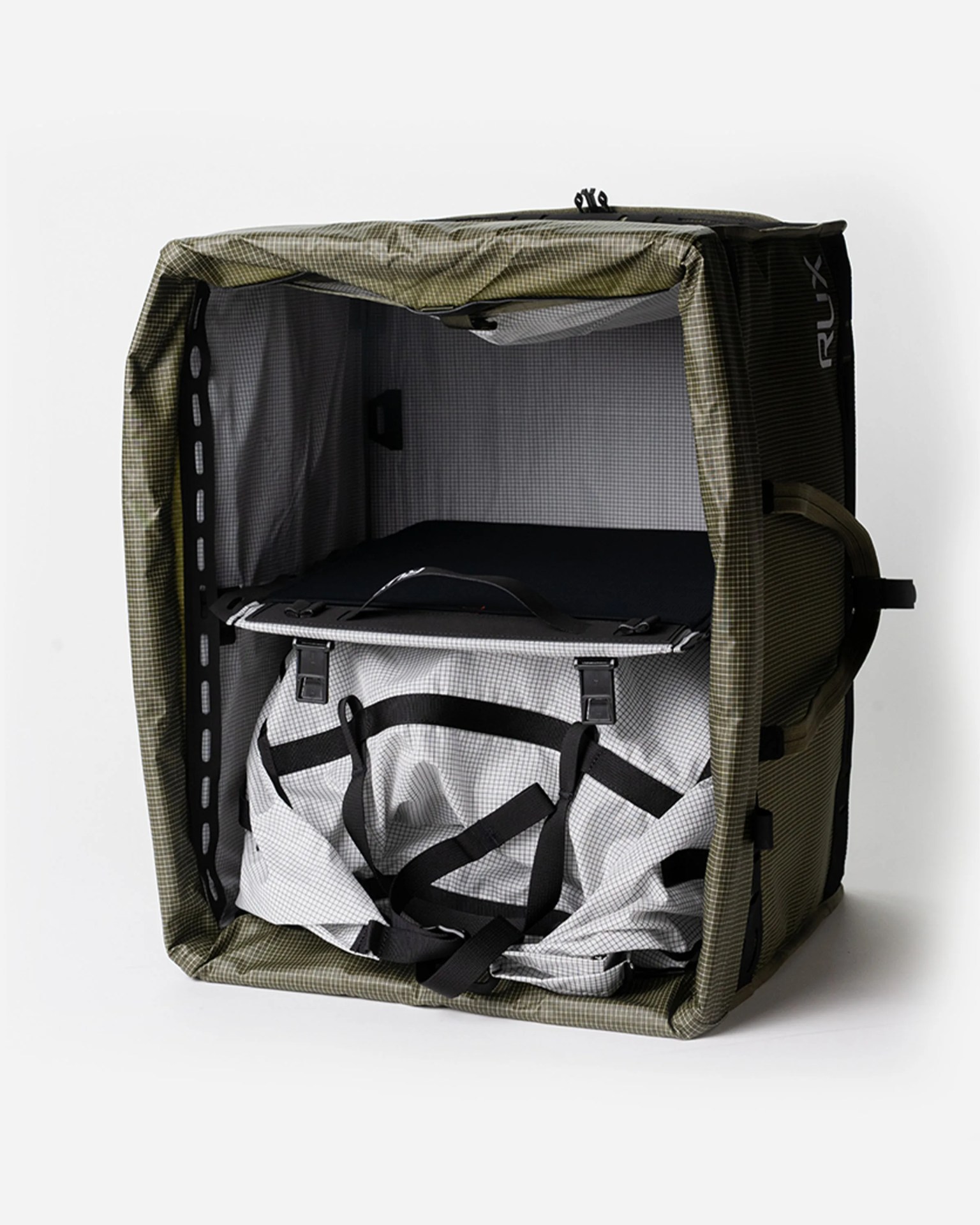 Green and black RUX soft-sided bike travel case with a white duffel bag inside.