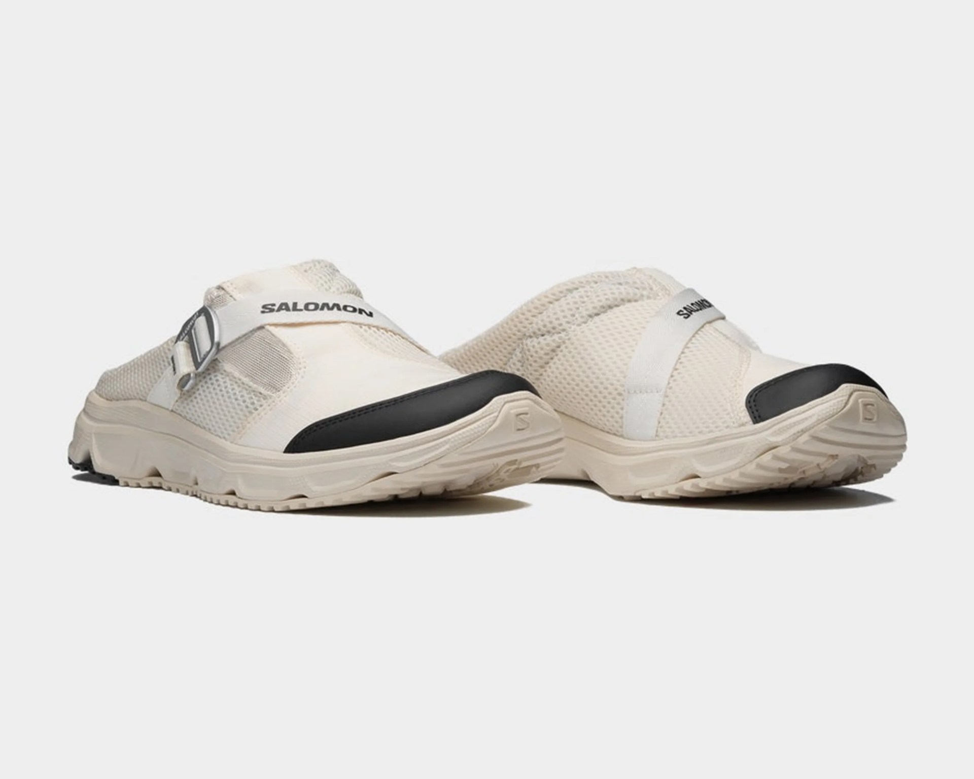 Pair of off-white Salomon slip-on sandals with mesh uppers, black toe caps, and adjustable straps.