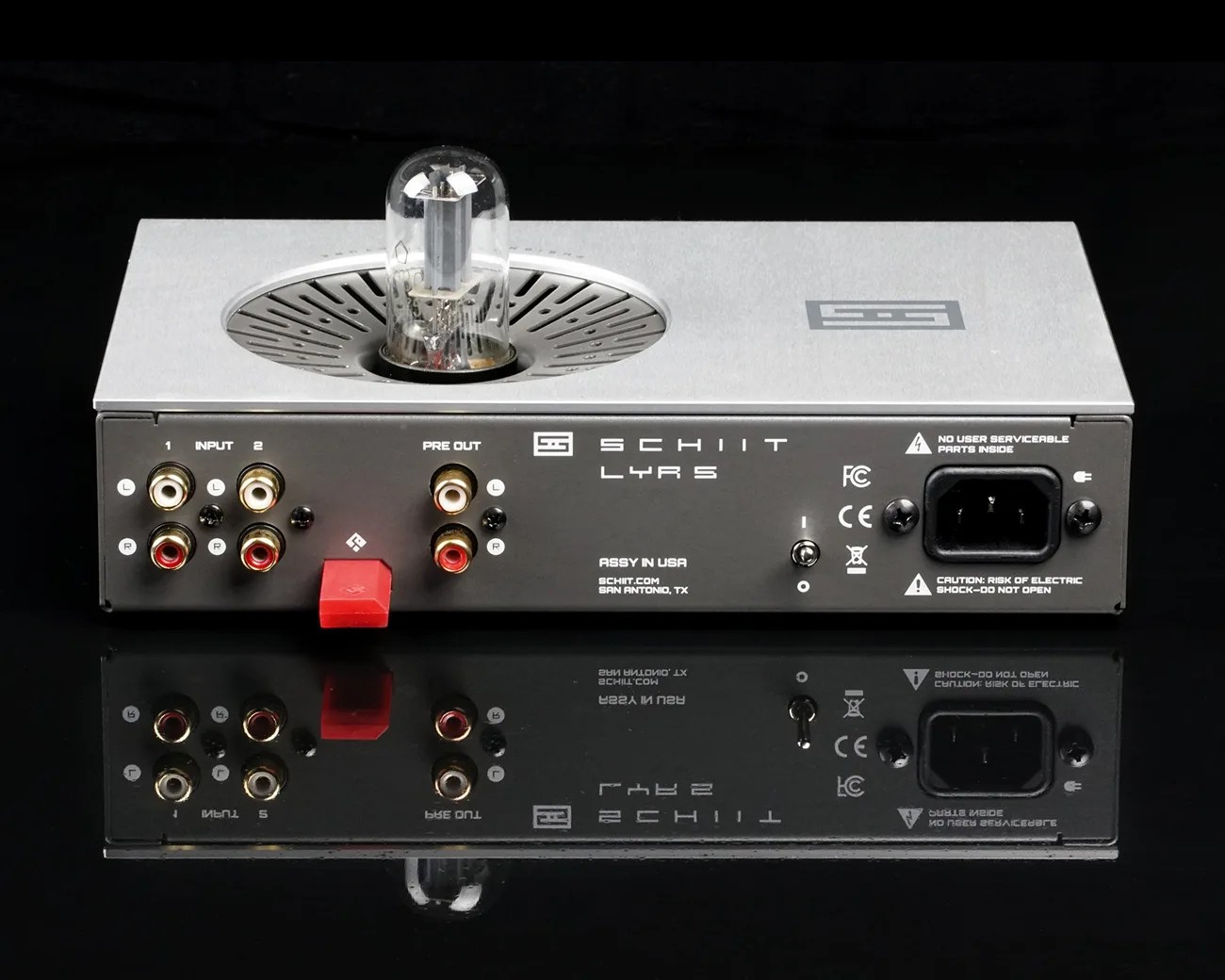 Rear view of a silver Schiit Lyr 5 headphone amplifier with RCA inputs, pre-out, USB port, power switch, and power socket on a reflective black surface.