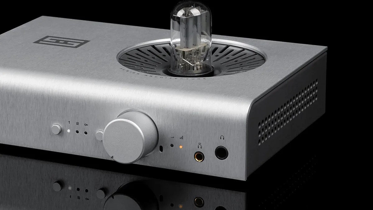 Silver brushed metal audio amplifier with a large central knob and a visible vacuum tube on top.