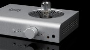 Silver brushed metal audio amplifier with a large central knob and a visible vacuum tube on top.