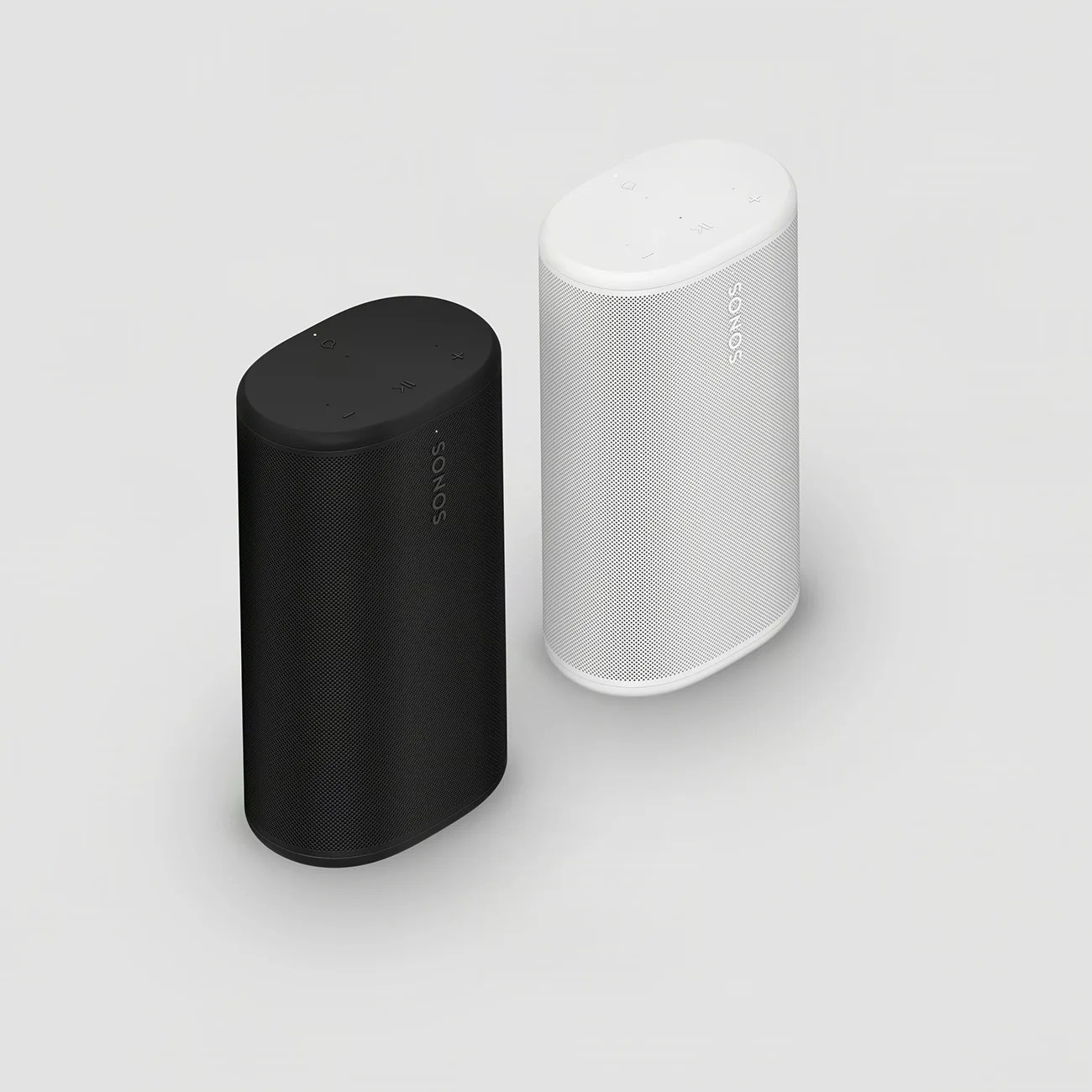 Two Sonos wireless speakers, one black and one white, standing upright on a light gray surface.