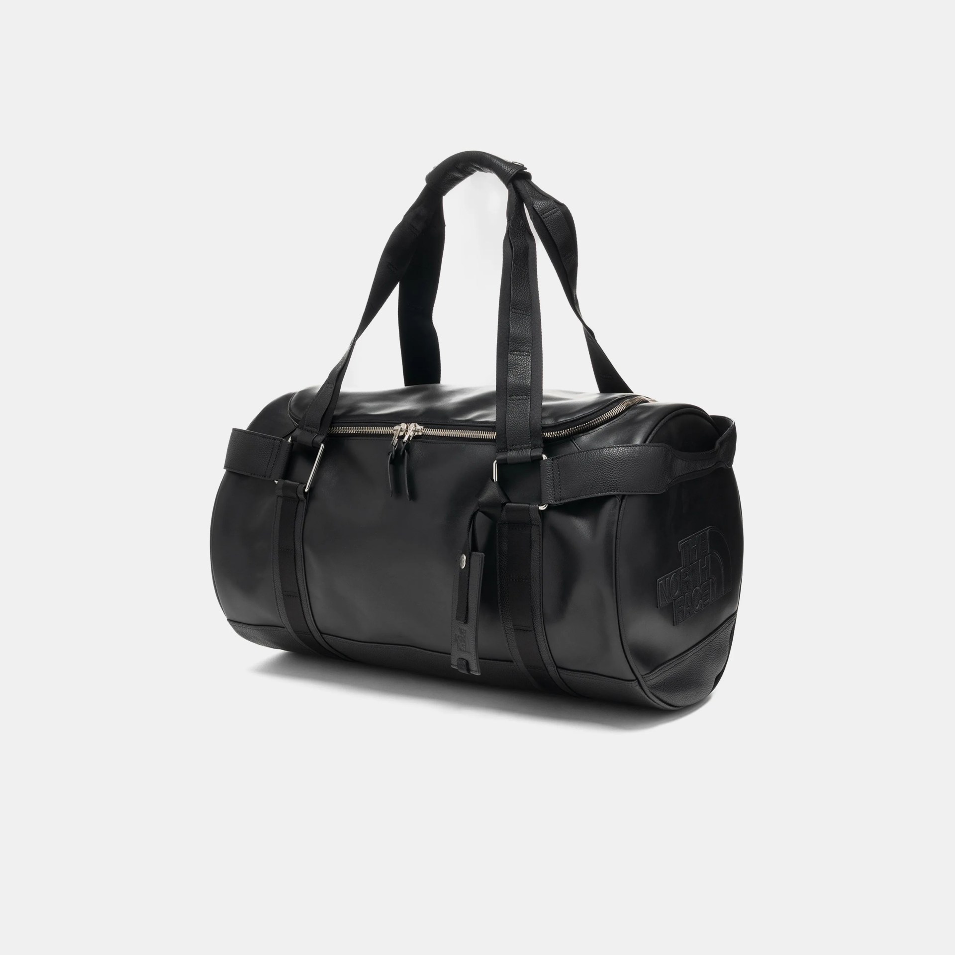 Black cylindrical duffel bag with dual handles and embossed "The North Face" logo on the side.