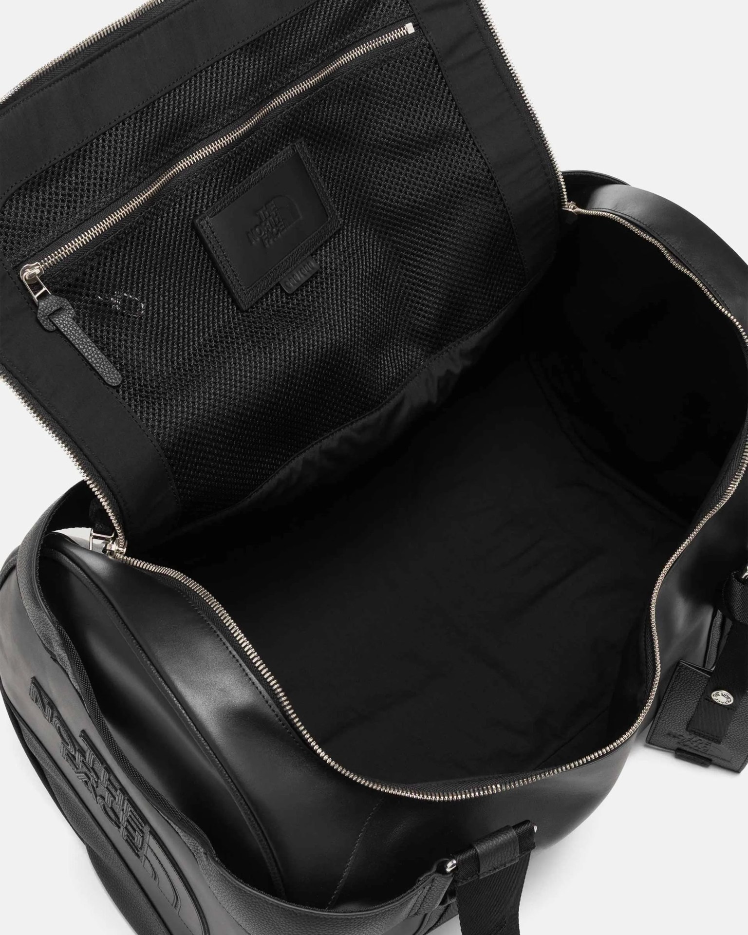 Black leather duffel bag with silver zipper and mesh zippered pocket inside the lid.