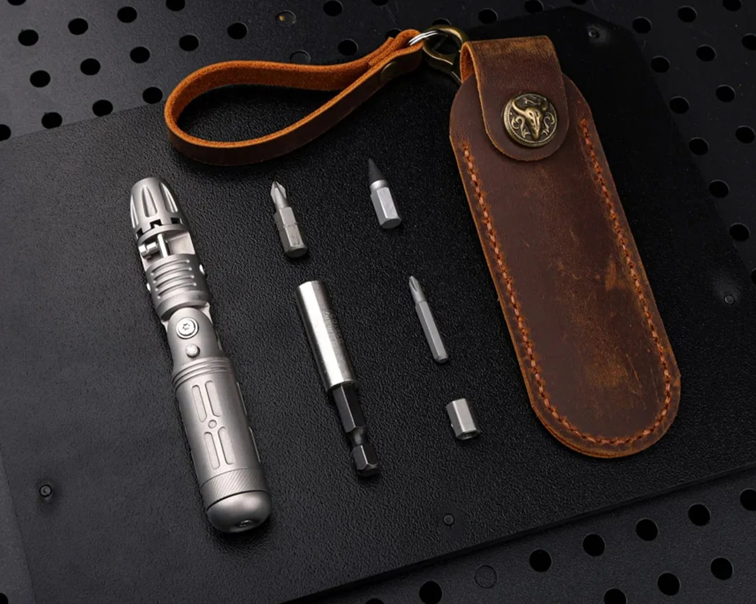 Compact silver multi-bit screwdriver with five bits and a brown leather carrying case with a strap.