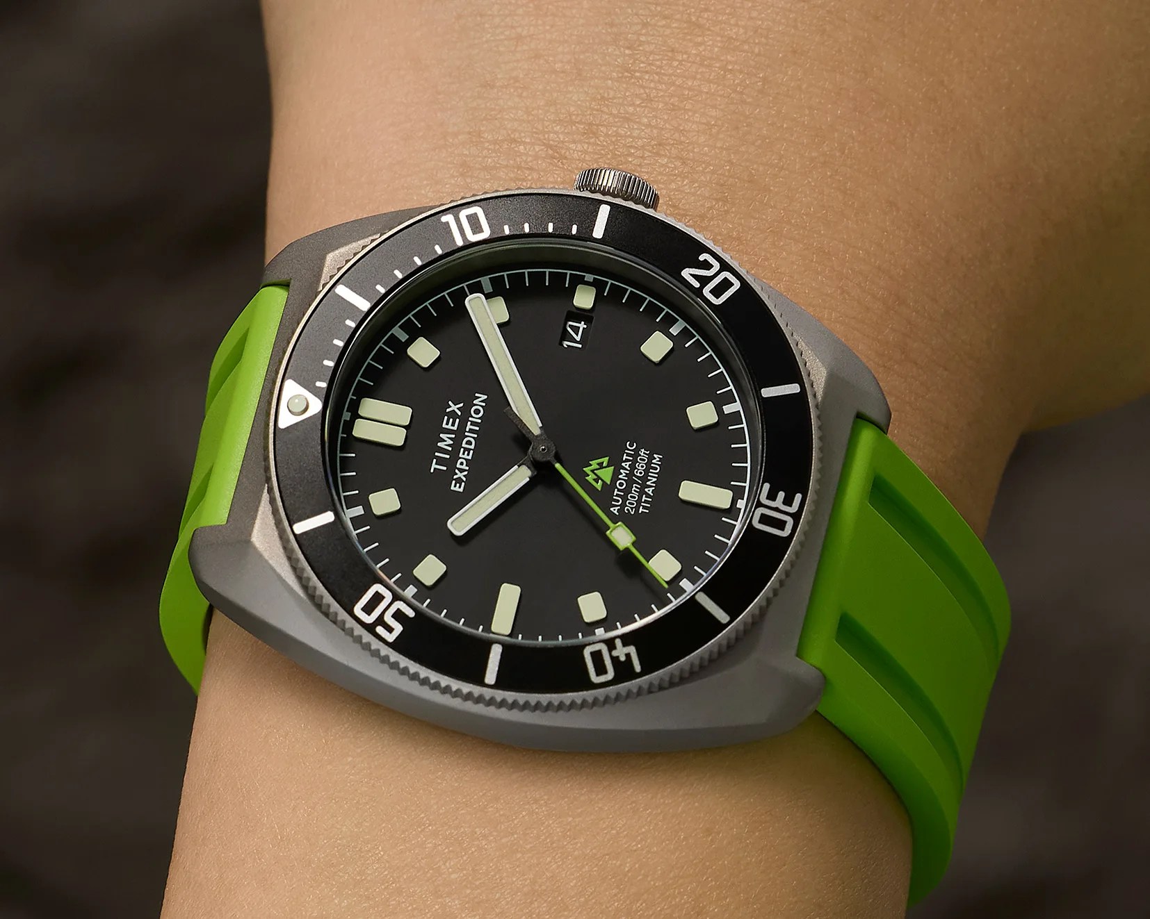 Timex Expedition watch with black dial, black bezel, titanium case, and bright green rubber strap on a wrist.