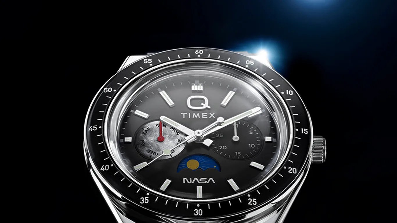 Close-up of a Timex Q NASA watch with black dial, silver markers, two subdials, and a sun-moon indicator.