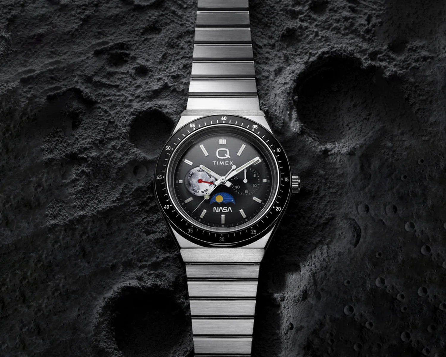 Silver metal Timex wristwatch with black dial featuring NASA logo and sun-moon indicator on a cratered lunar surface background.