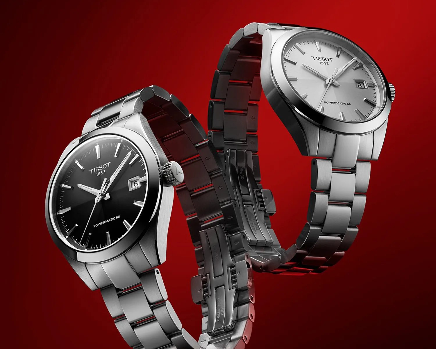 Two stainless steel Tissot Powermatic 80 wristwatches with black and white dials on a red background.