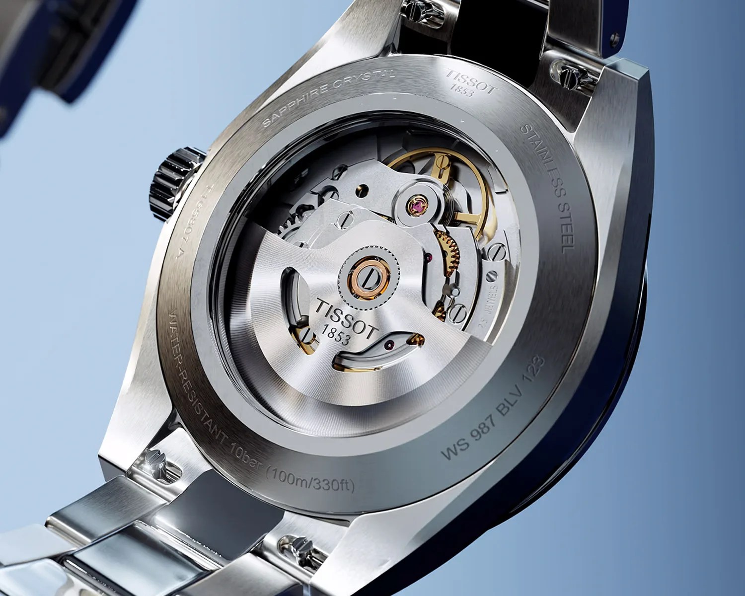 Close-up of the back of a Tissot stainless steel watch showing its automatic movement through a sapphire crystal caseback.