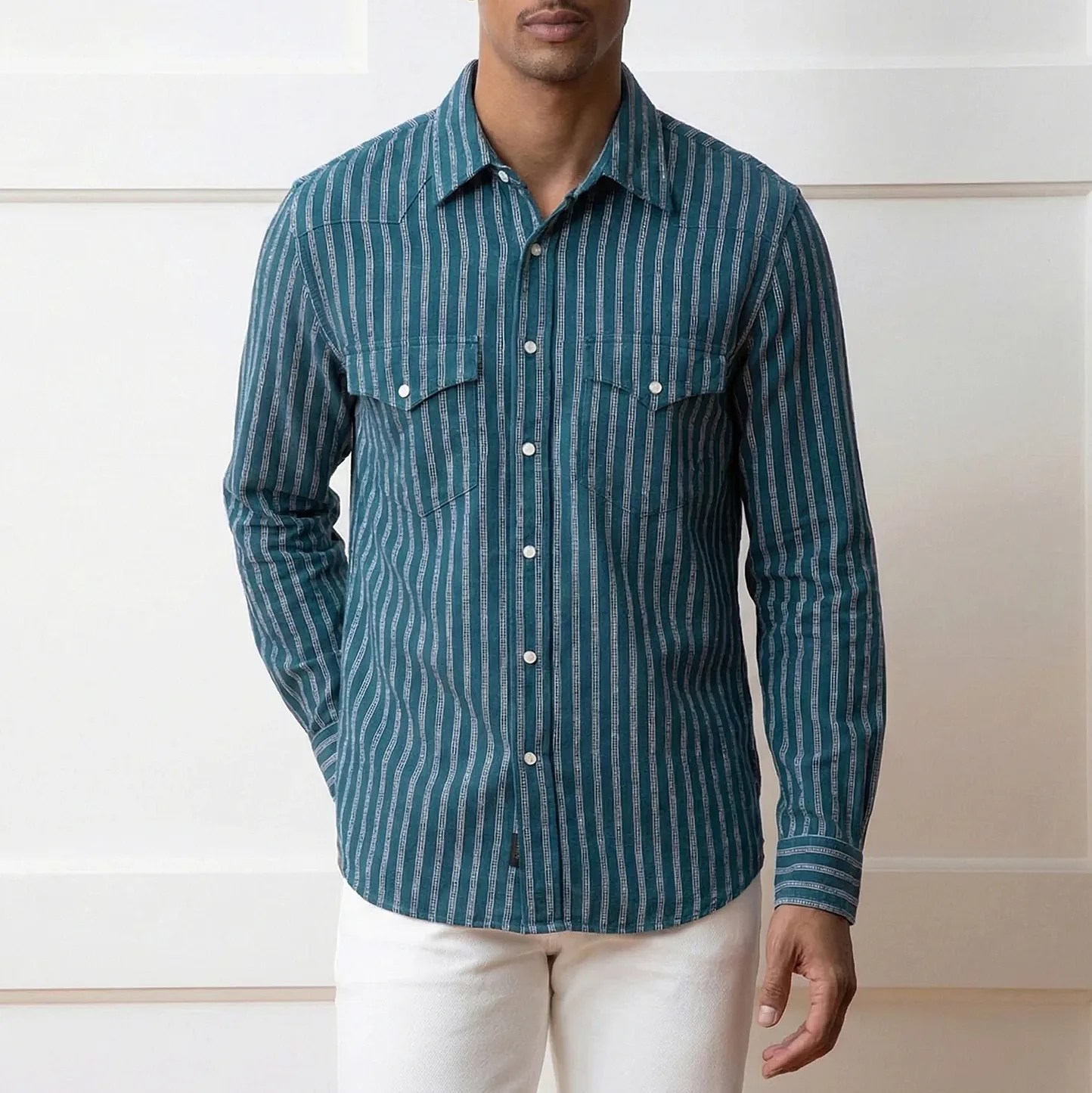 Teal long-sleeve button-up shirt with vertical white stripes and chest pockets worn by a person.