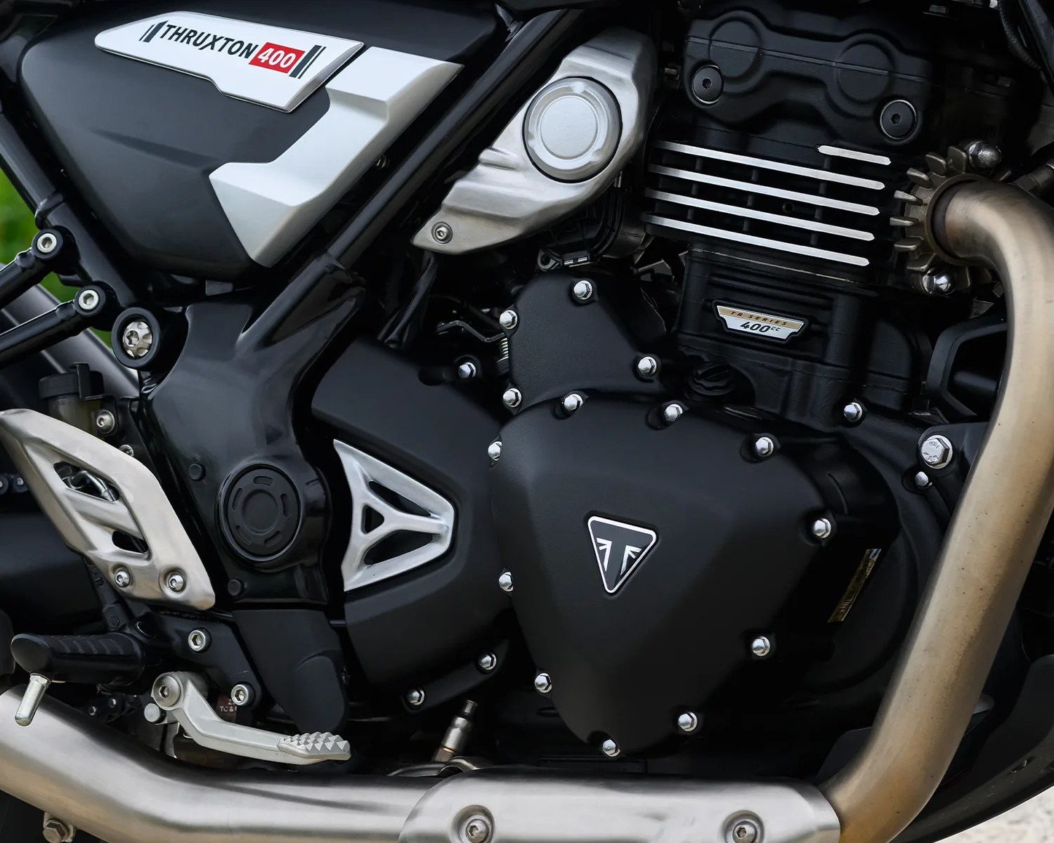 Close-up of a black and silver Triumph Thruxton 400 motorcycle engine with visible "400 cc" and Triumph logo.