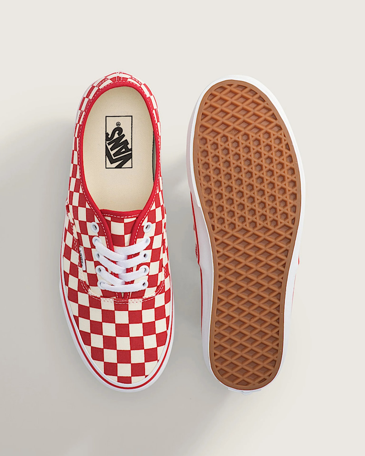 Pair of red and white checkered Vans sneakers, one showing top view and the other showing the brown waffle sole.